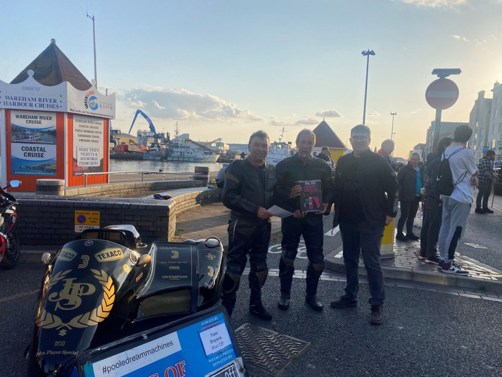 three men posing with winning bike and Poole quay 